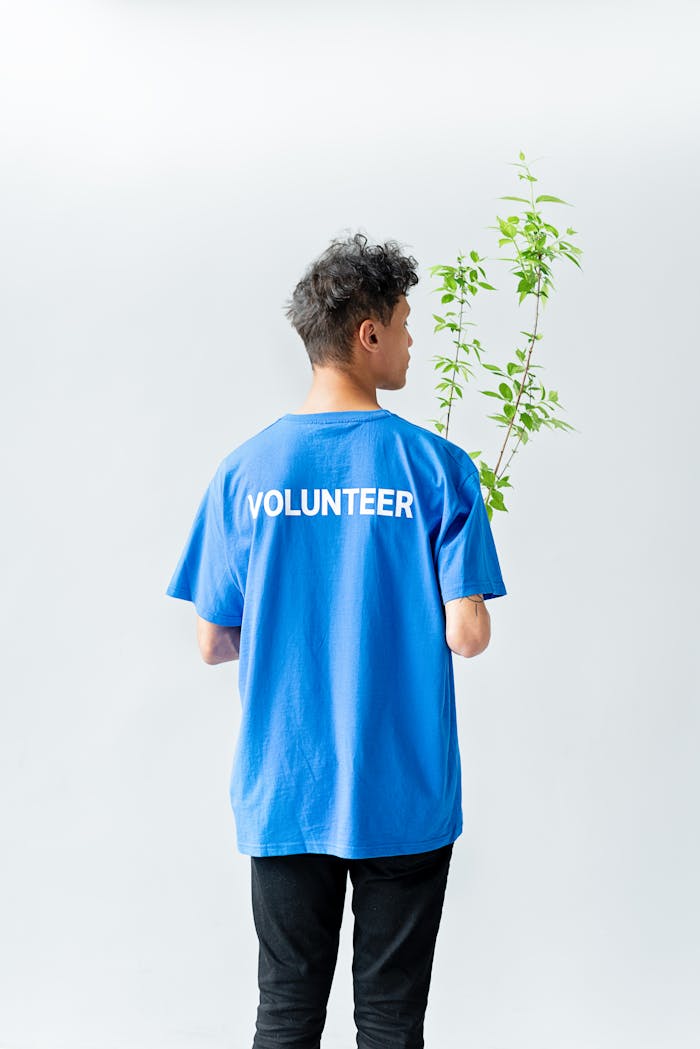 Man in Blue Crew Neck T-shirt Standing With a Green Plant